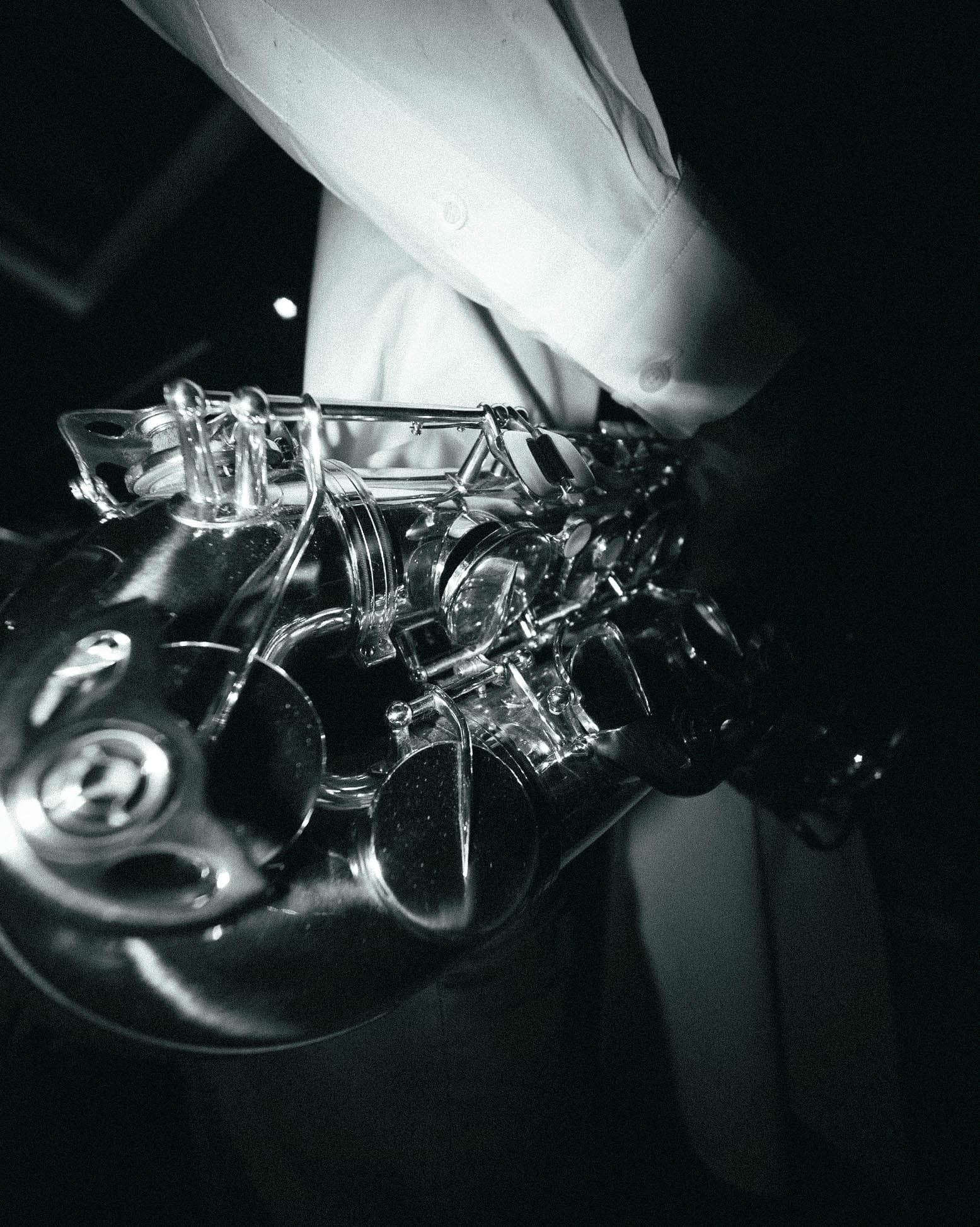 Close-up of a tenor saxophone held against a white shirt